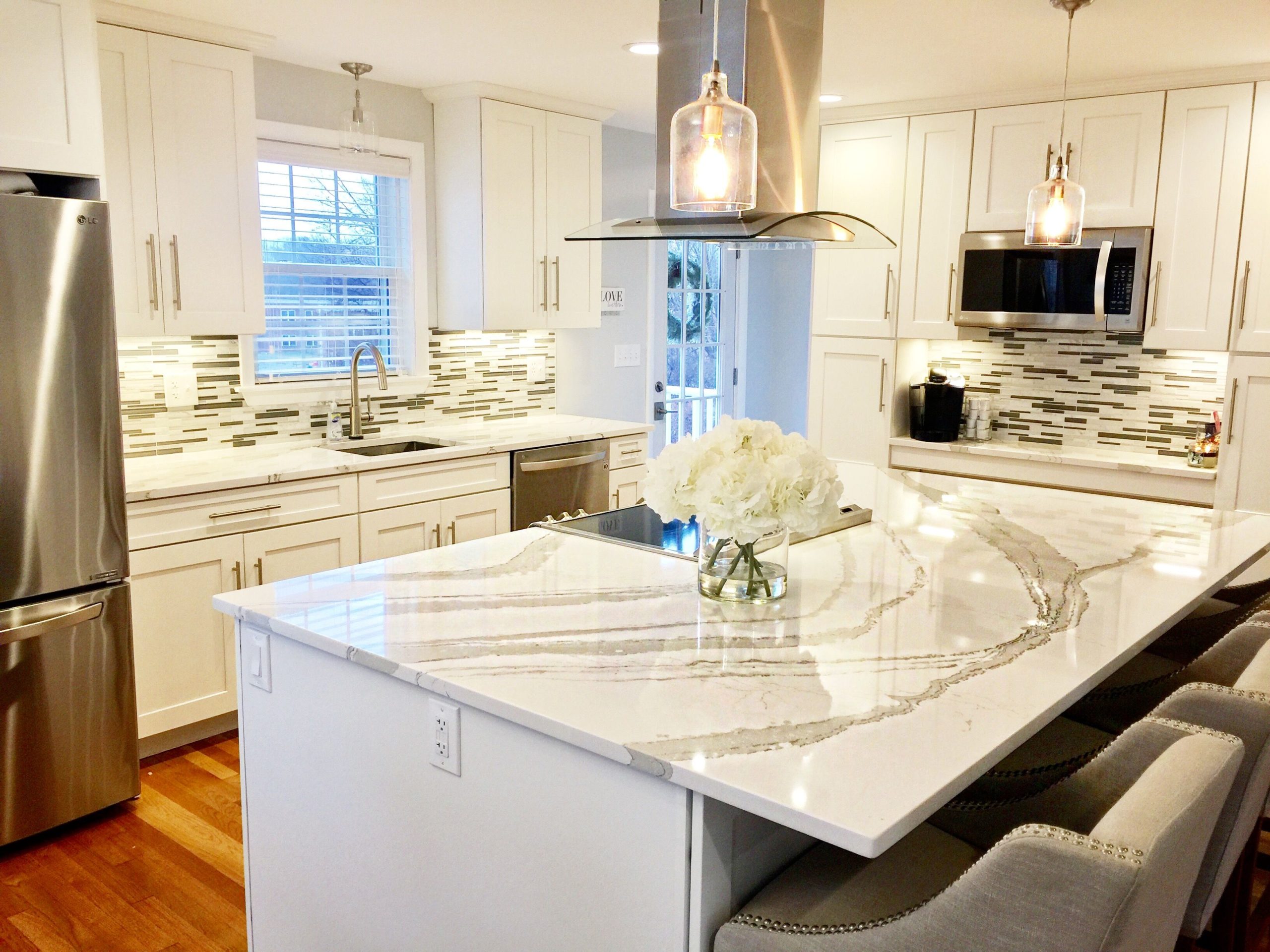 Brittanicca Warm Cambria Quartz Kitchen Countertops with White Cabinets, Stainless Steel, and Bar Stools