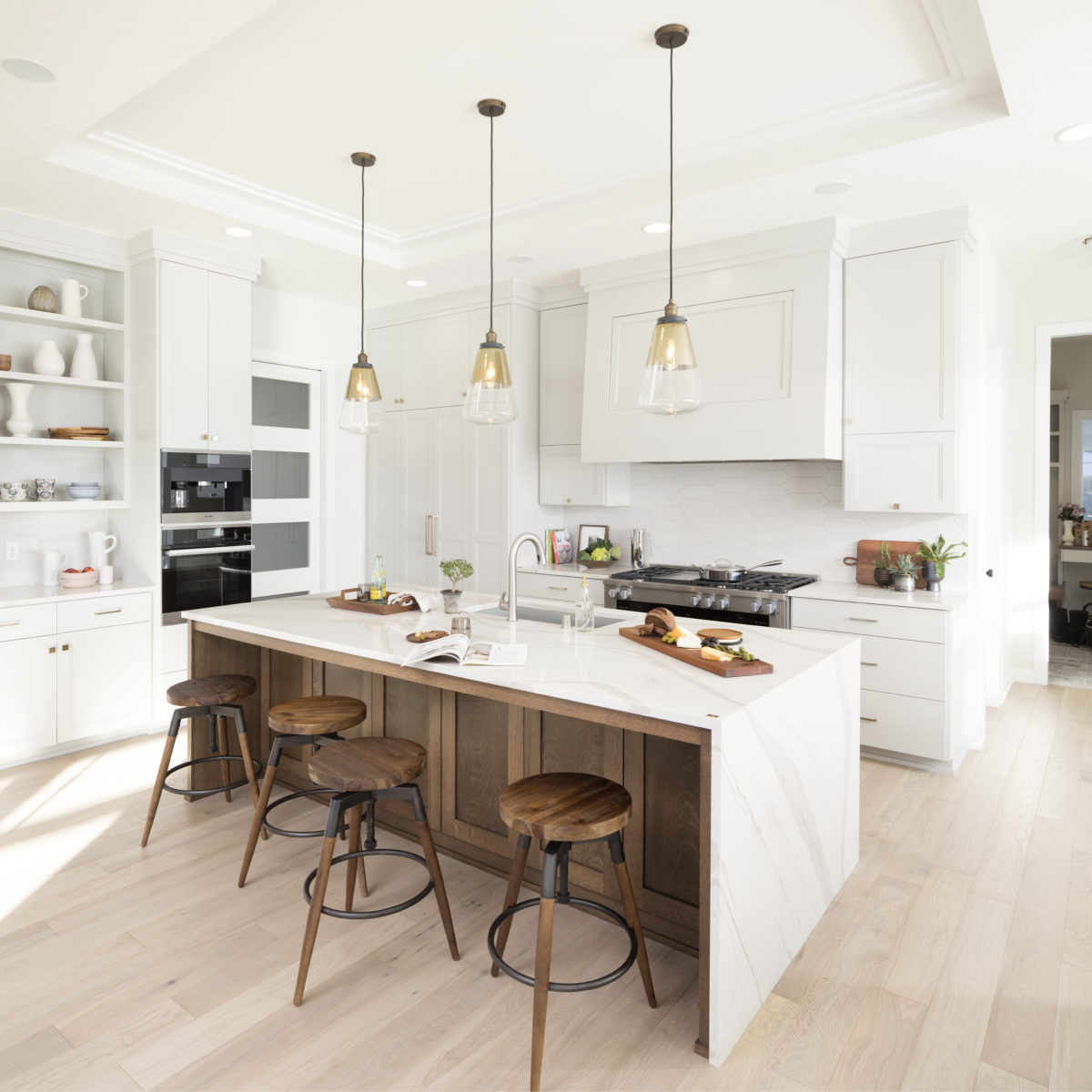 Brittanicca Warm Cambria Quartz Kitchen Countertops and Island with Waterfall Panel Edge pendant lighting white cabinets brown cabinets